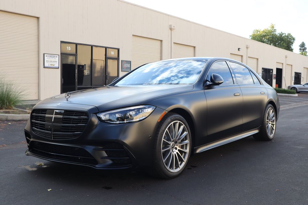 Front three-quarter view of a Mercedes-Benz S580 with a satin black wrap and full chrome delete by Drift Wraps