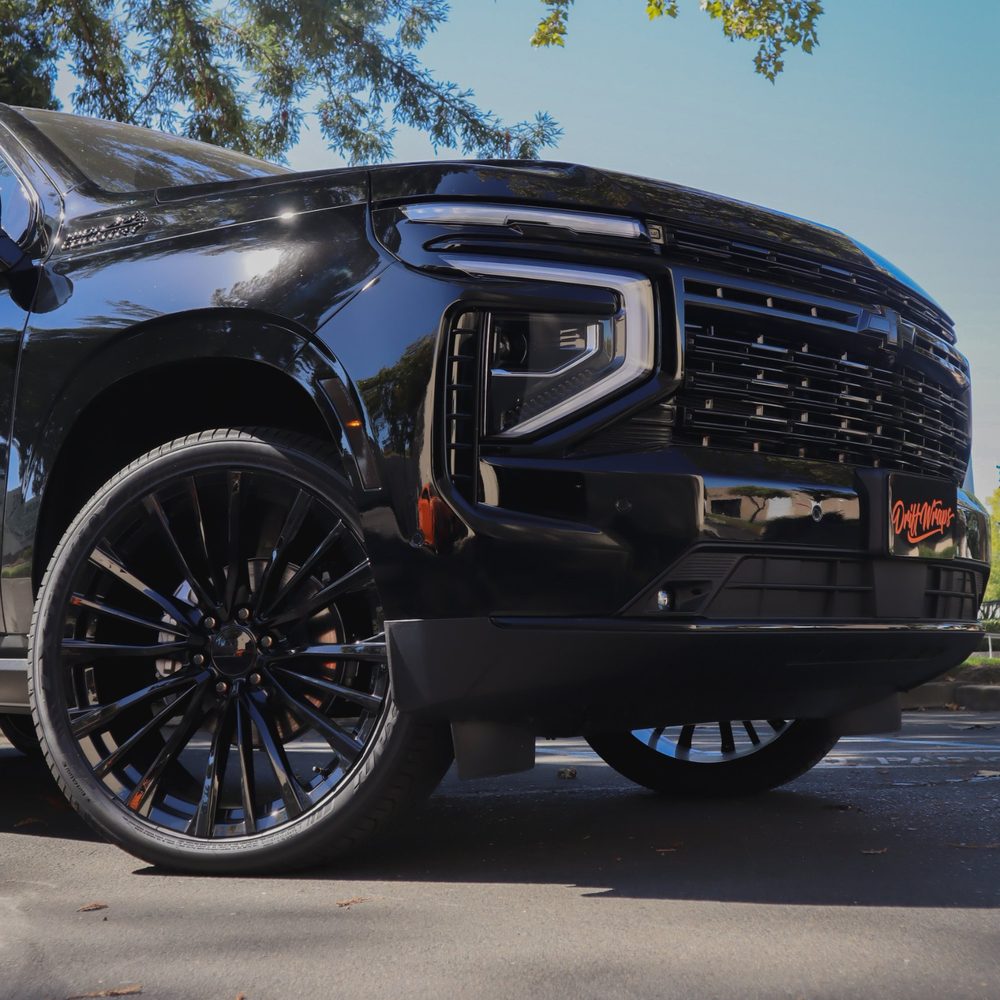 Low front view of a black Chevrolet Tahoe High Country with blacked-out grille and trim after chrome delete by Drift Wraps in Rancho Cordova