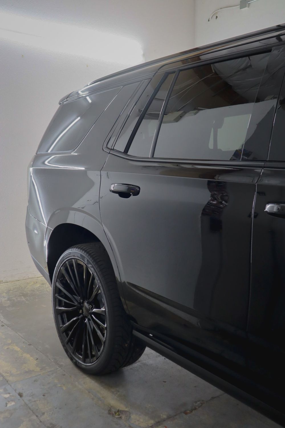 Rear quarter, blacked-out wheel accents and window trim of a Chevrolet Tahoe High Country with gloss black chrome delete by Drift Wraps