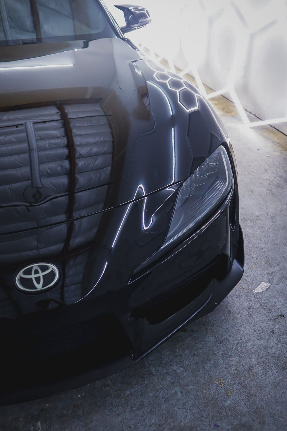 Hood and headlight close-up on a black 2020 Toyota GR Supra wrapped in Gloss Black Obsidian color PPF by Drift Wraps in Rancho Cordova