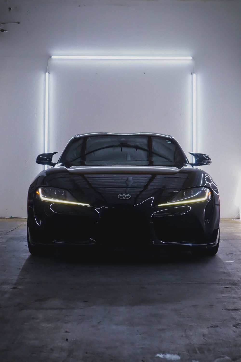 Front of a black 2020 Toyota GR Supra wrapped in Gloss Black Obsidian color PPF by Drift Wraps in Rancho Cordova with headlights on in the studio