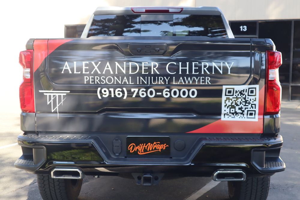 Tailgate lettering and QR code on an Alexander Cherny Personal Injury Lawyer Chevrolet Silverado Z71 with a custom design 2/3 wrap by Drift Wraps in Rancho Cordova outside the Drift Wraps shop