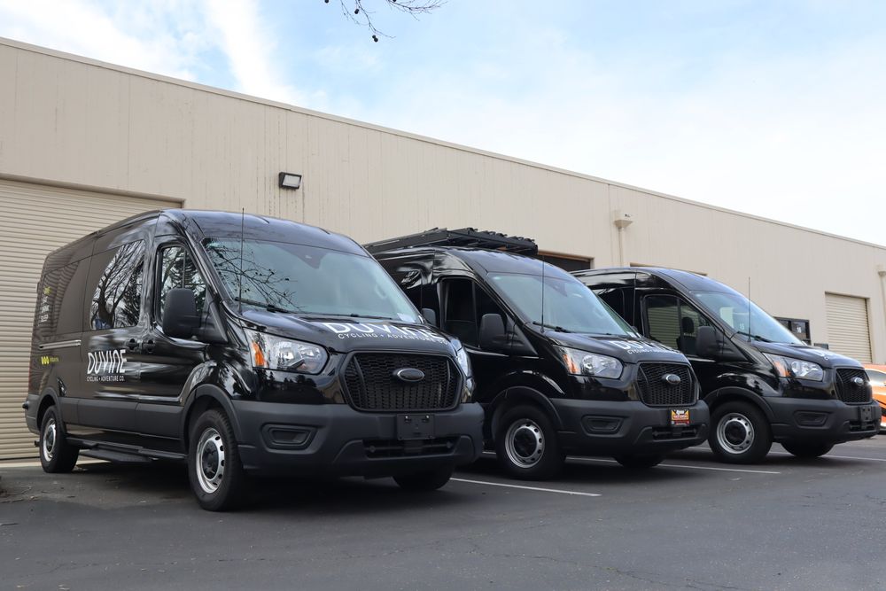 Three DuVine Cycling + Adventure Co. Ford Transit vans with a full wrap and custom decal text by Drift Wraps in Rancho Cordova