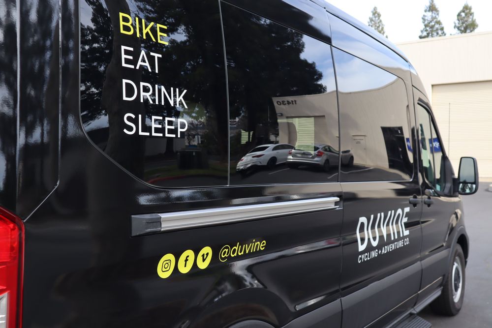 Window lettering on the side of a DuVine Cycling + Adventure Co. Ford Transit van with a full wrap and custom decal text by Drift Wraps in Rancho Cordova