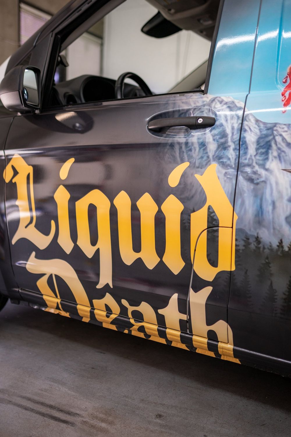 Gold lettering on the front door of a Liquid Death Mercedes-Benz Metris van with a themed full wrap by Drift Wraps in Rancho Cordova