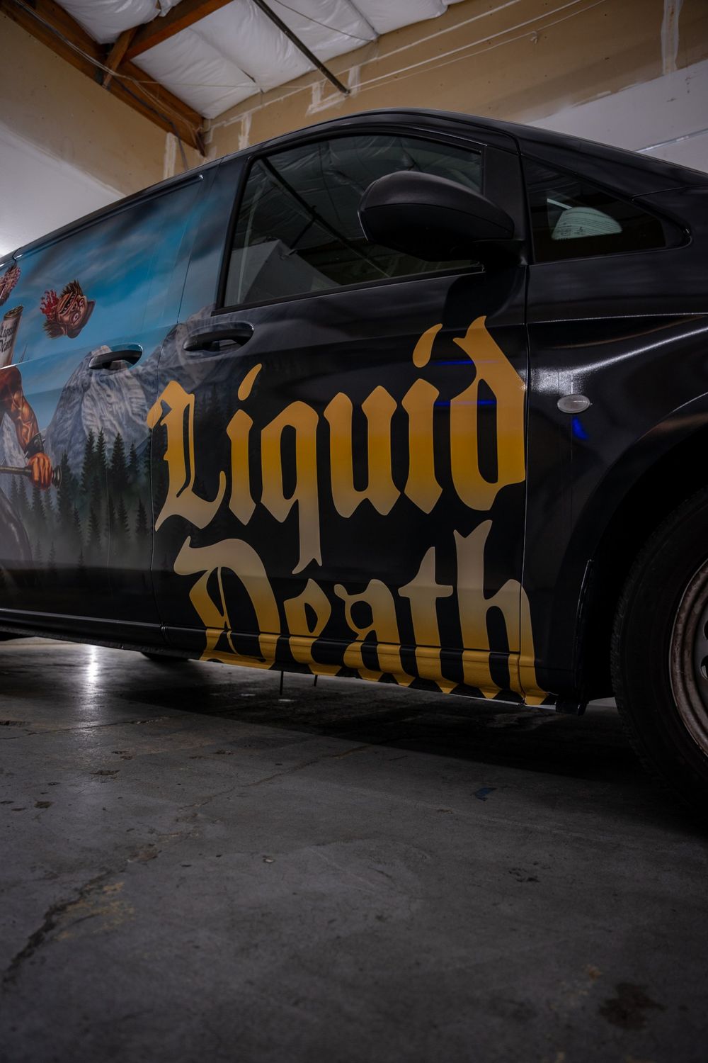 Low angle of the gold lettering on a Liquid Death Mercedes-Benz Metris van with a themed full wrap by Drift Wraps in Rancho Cordova