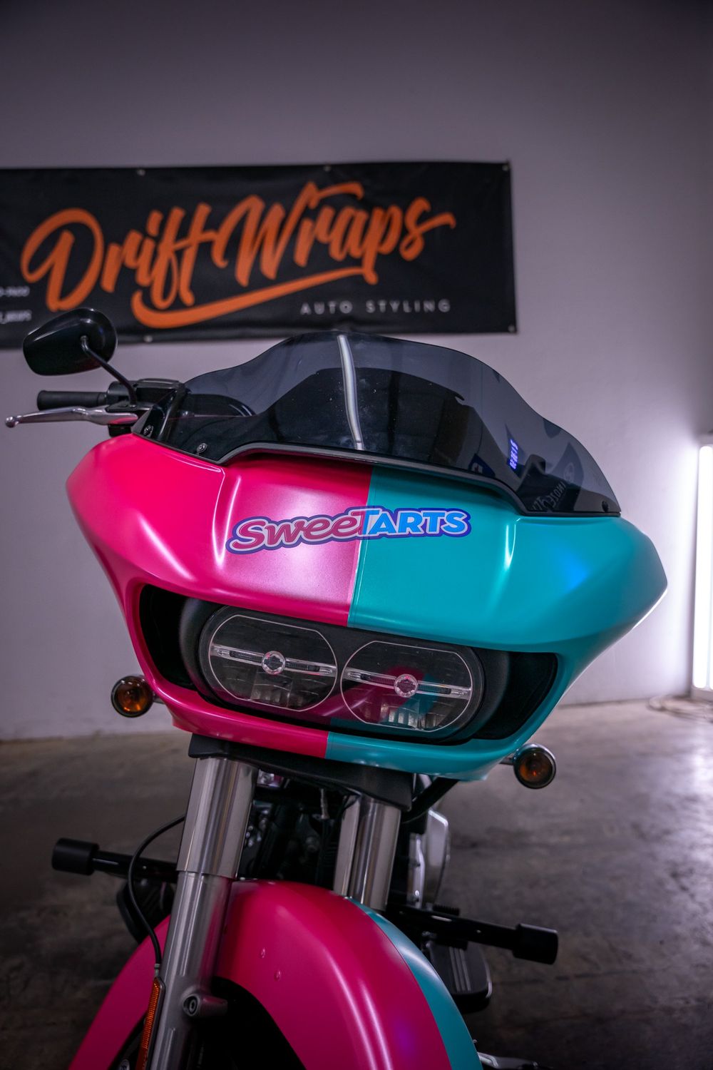 Custom decal on the fairing of a Harley-Davidson Road Glide with a half pink, half teal themed wrap by Drift Wraps