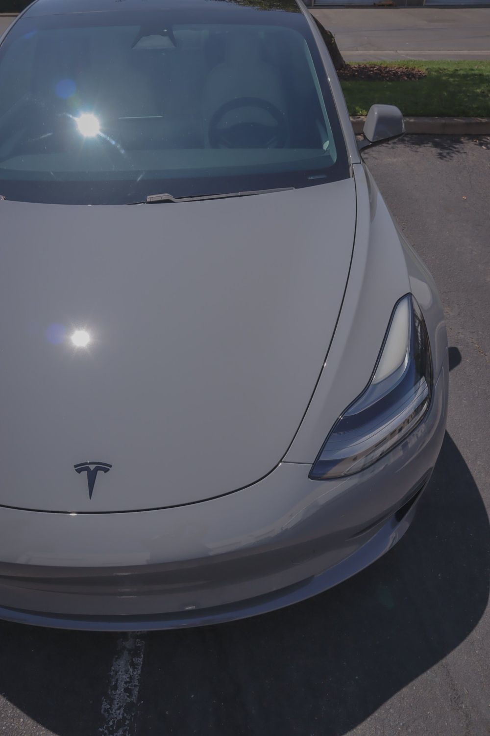 Hood and headlight of a Tesla Model 3 wrapped in 3M High Gloss Nardo Gray by Drift Wraps