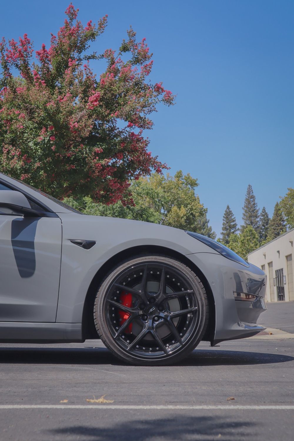 Front wheel of a Tesla Model 3 wrapped in 3M High Gloss Nardo Gray by Drift Wraps
