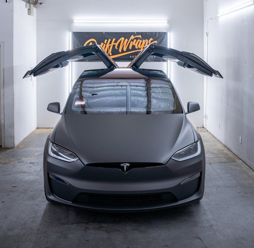 Falcon Wing doors up on a Tesla Model X wrapped in 3M Dead Matte Black by Drift Wraps in the Drift Wraps shop