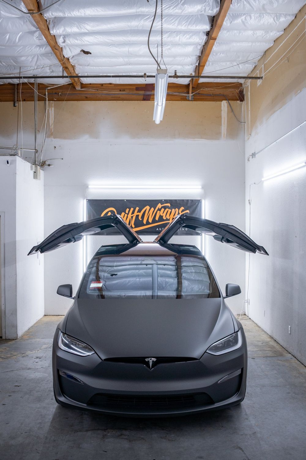 Falcon Wing doors up on a Tesla Model X wrapped in 3M Dead Matte Black by Drift Wraps