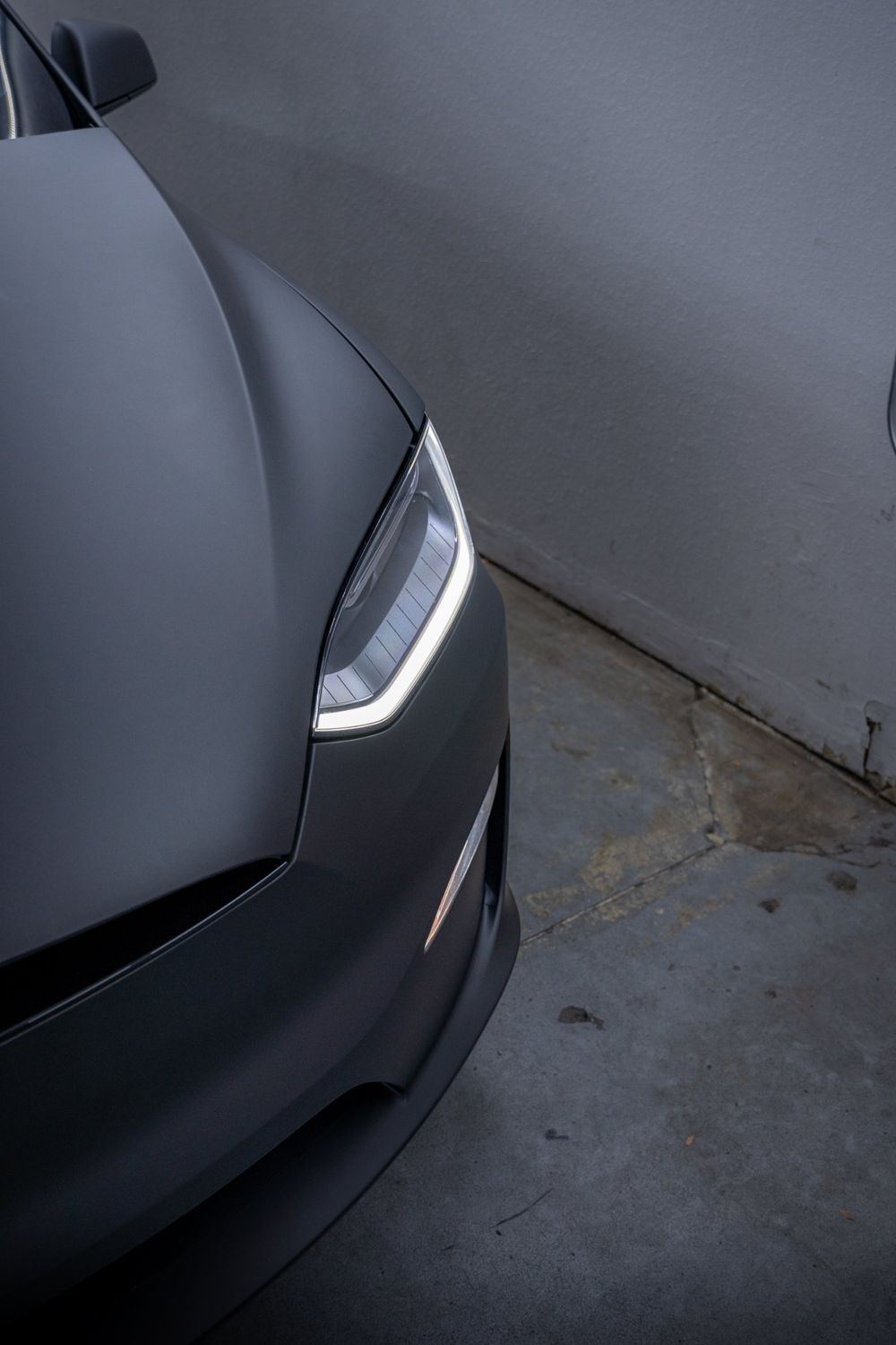 Headlight close-up on a Tesla Model X wrapped in 3M Dead Matte Black by Drift Wraps