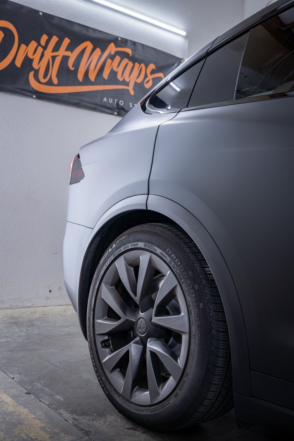 Rear wheel and quarter panel of a Tesla Model X wrapped in 3M Dead Matte Black by Drift Wraps