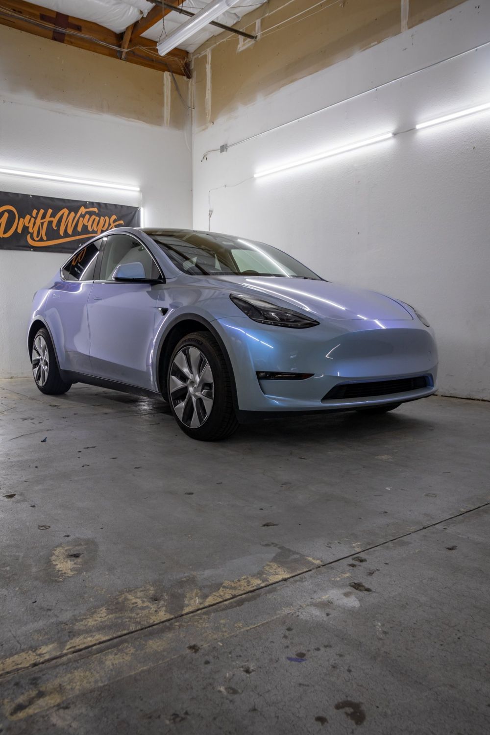 Front three-quarter view of a Tesla Model Y wrapped in TeckWrap Gloss Azure Maya Blue by Drift Wraps