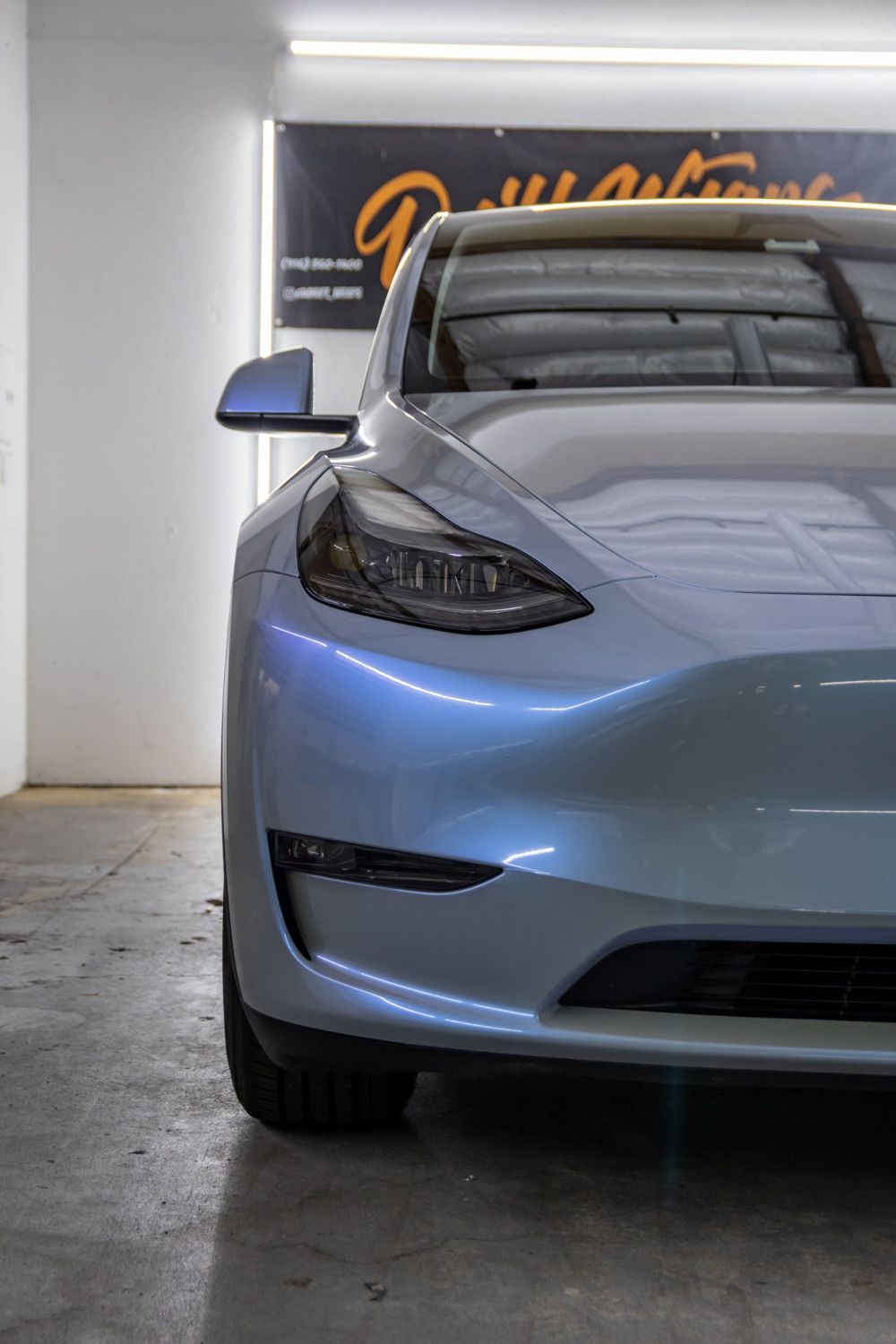 Headlight close-up on a Tesla Model Y wrapped in TeckWrap Gloss Azure Maya Blue by Drift Wraps