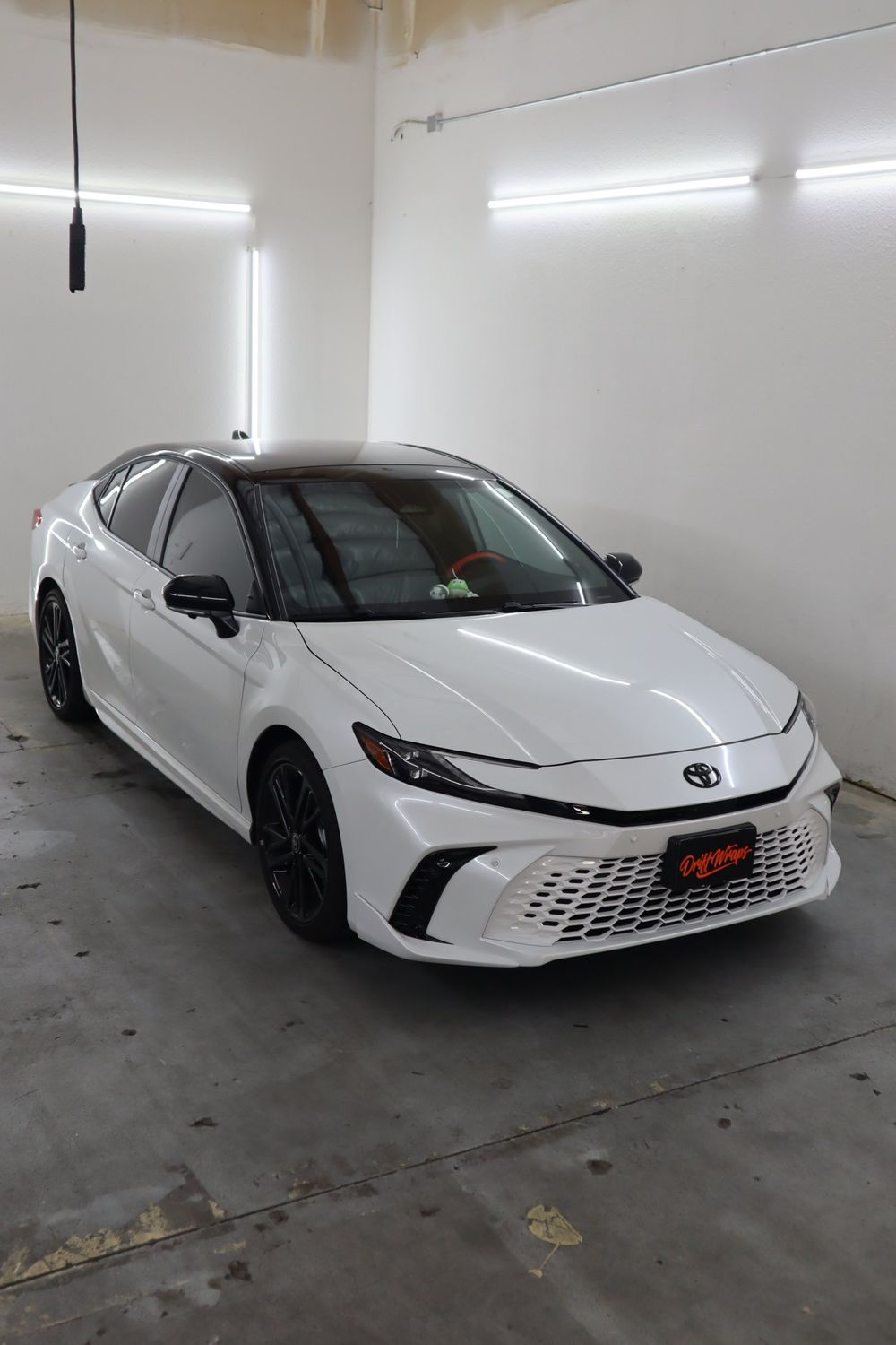 Front three-quarter view of a white Toyota Camry with LLumar ceramic window tint by Drift Wraps in Rancho Cordova