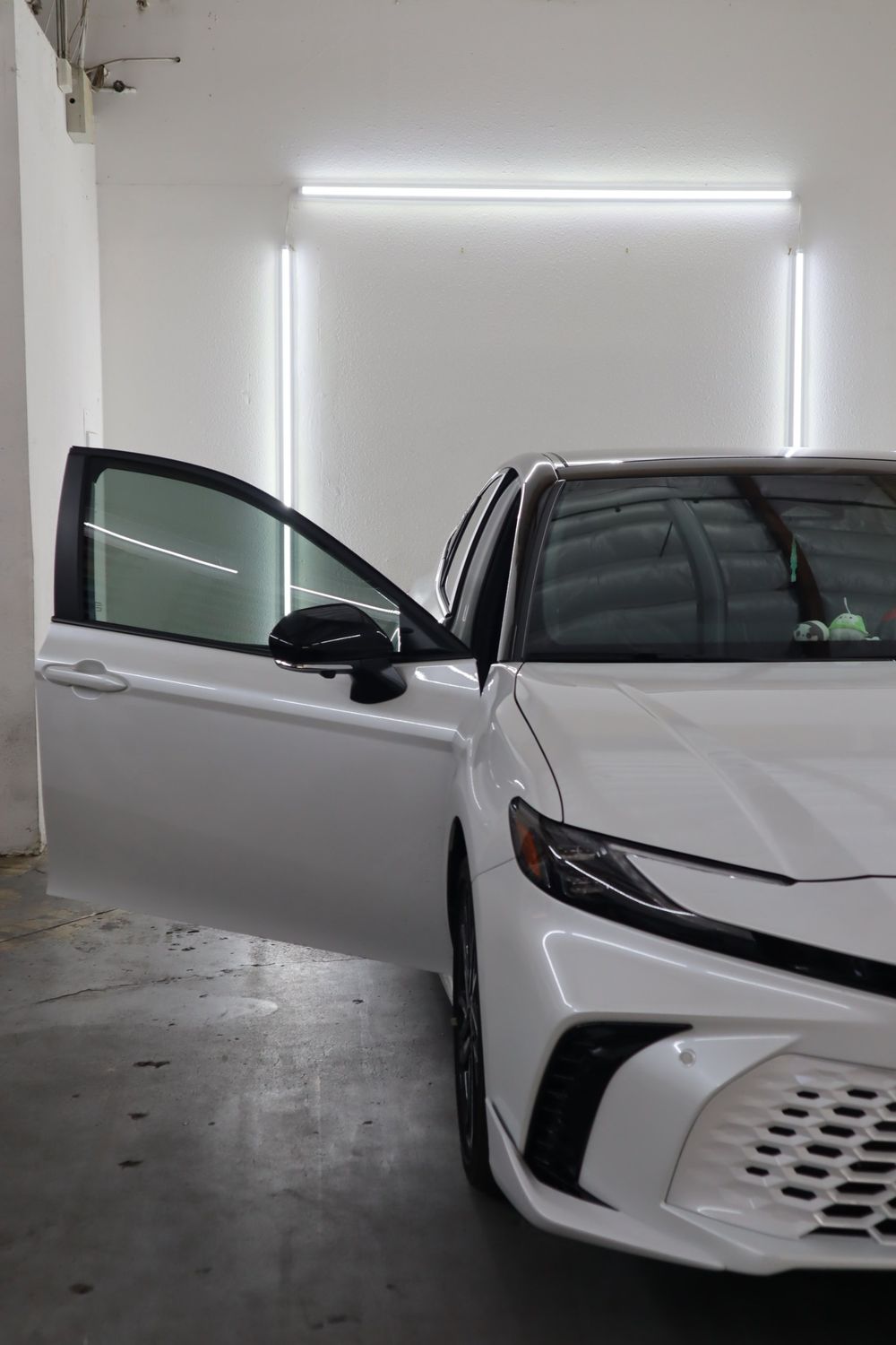 Tinted front door window on a white Toyota Camry with LLumar ceramic window tint by Drift Wraps in Rancho Cordova
